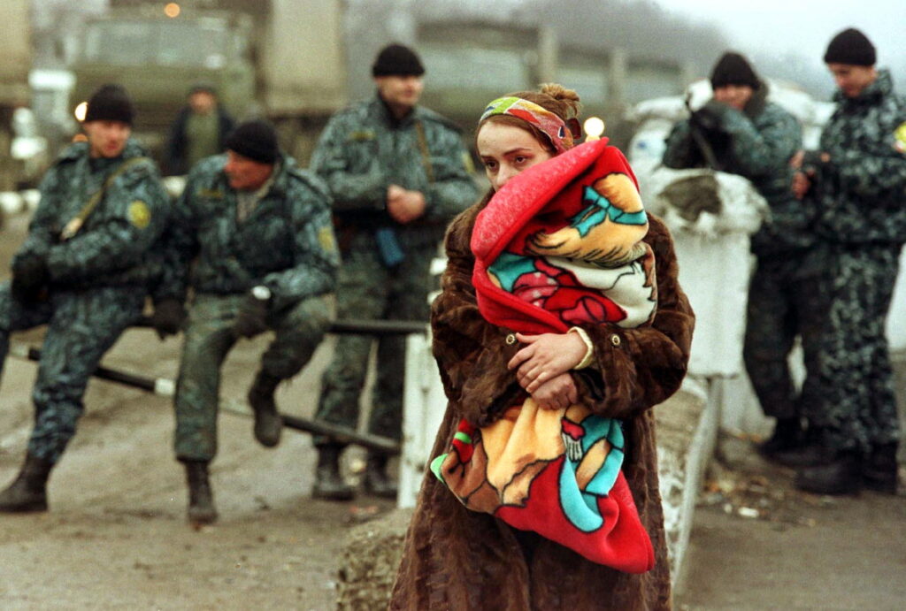 A CHECHEN REFUGEE WOMAN HOLDS HER BABY RETURNING